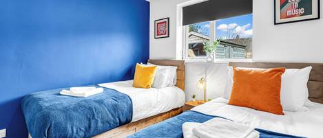 Una habitación de hotel con dos camas, una ventana con vistas, un cuadro en la pared y una mesita de noche con una lámpara.