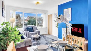A modern living room with a blue accent wall, a fireplace, and a dining area set with plates and glasses.