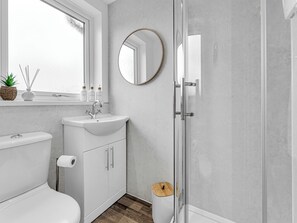 Une salle de bain équipée de toilettes, d’un lavabo, d’un miroir et d’une douche.