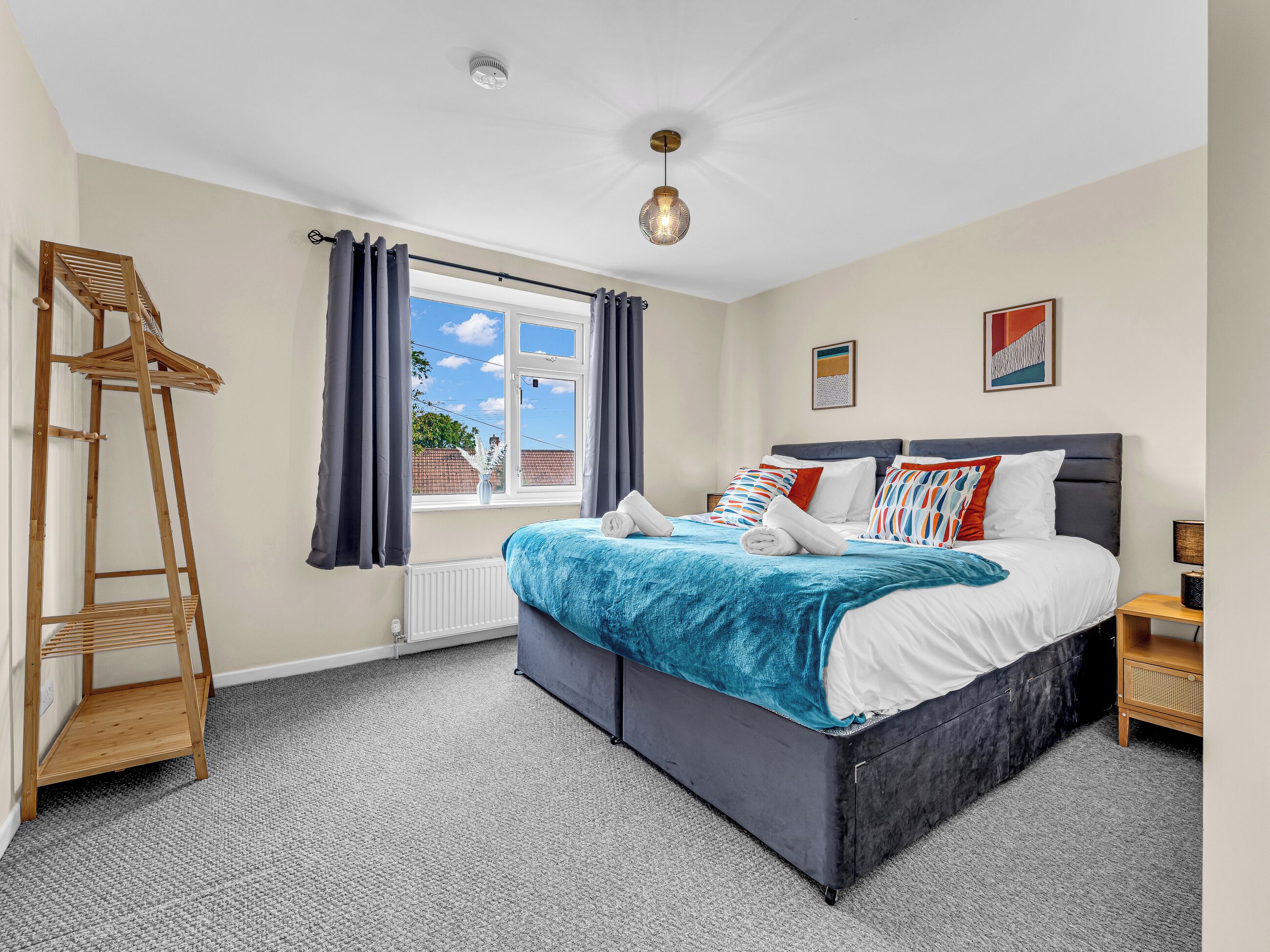 Un dormitorio con cama, ventana, radiador, estante de madera y lámpara.