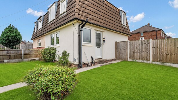 A two-story house with a sloped roof, a front door, and a small front yard with a hedge. - 3 bedroom accommodation in Leek (Leek)
