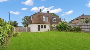 A two-story house with a brown tiled roof, a visible chimney, and a fenced backyard with green grass. - 3 bedroom accommodation in Leek (Leek)