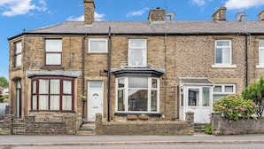 A two-story stone house with a bay window, a front door, and a small garden area. - A terraced cottage on Leek Road, positioned for Buxton and the Peak District. (Buxton)