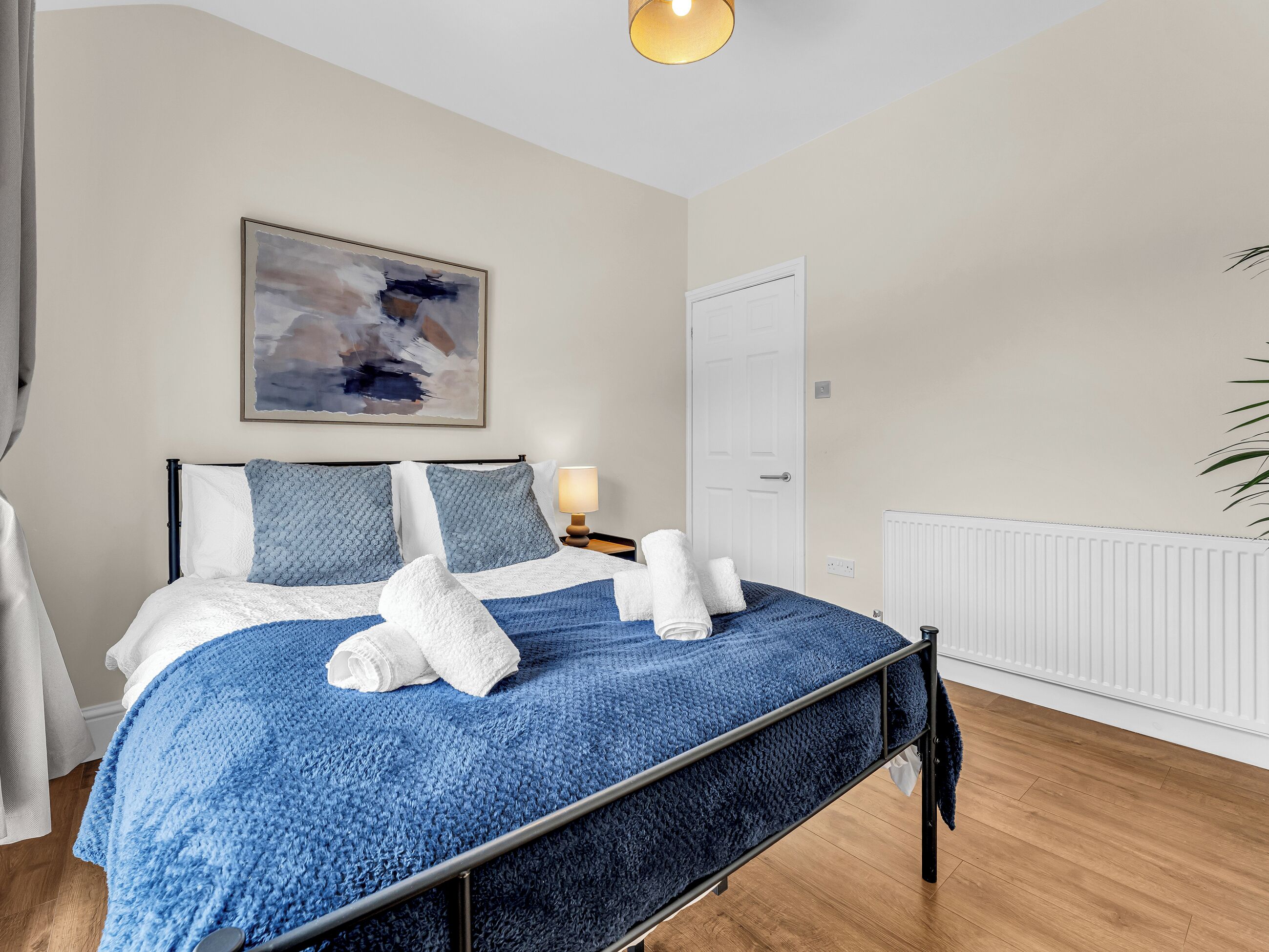 A bedroom with a bed, a painting, a door, and a radiator.