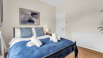 A bedroom with a bed, a painting, a door, and a radiator.