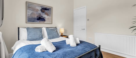 Un dormitorio con cama, un cuadro, una puerta y un radiador.