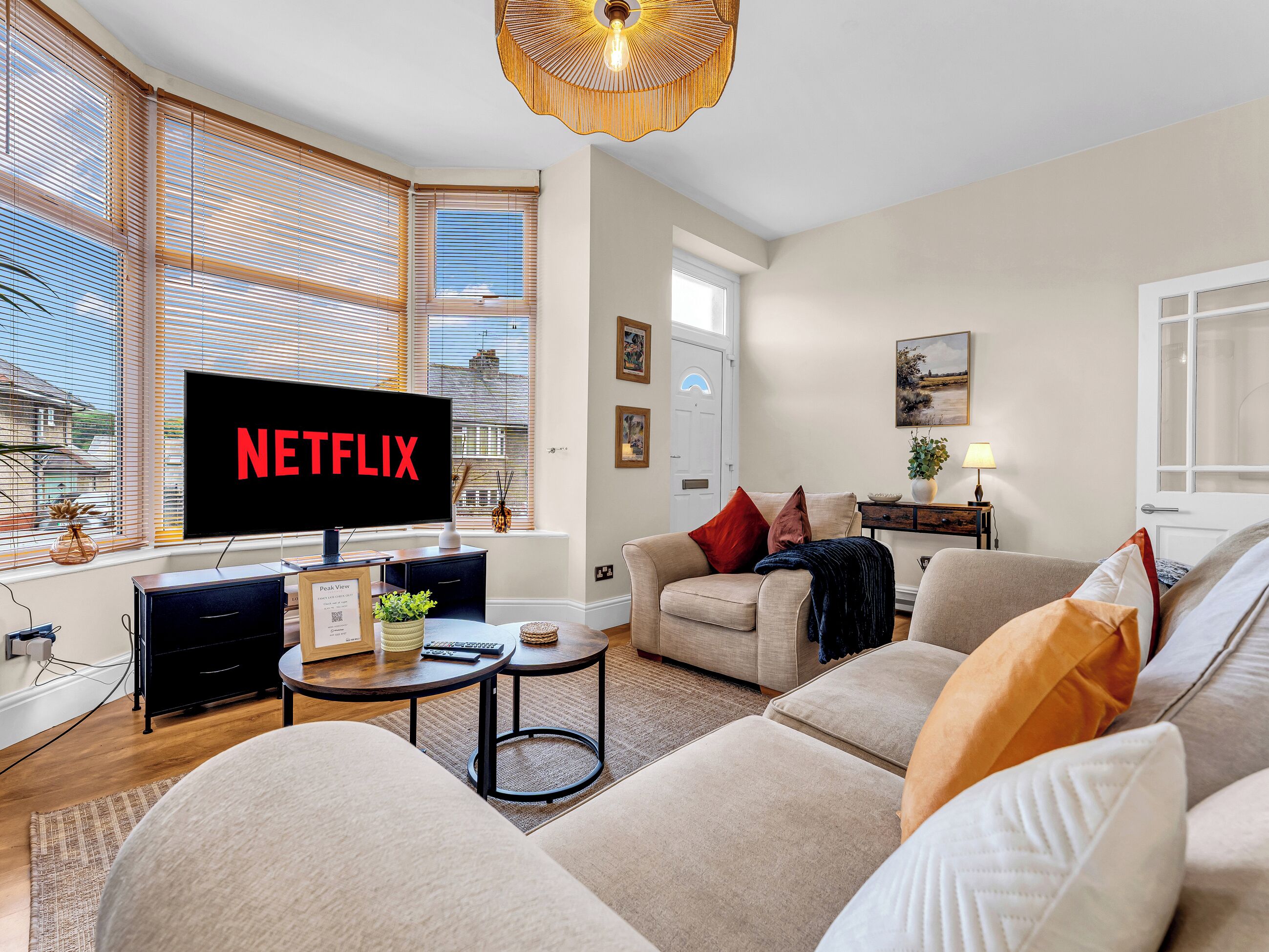 Una sala de estar con una televisión mostrando 'NETFLIX', un sofá, una mesa de centro y una lámpara.