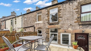 A stone house with a patio, outdoor seating, and a door with a window. - A terraced cottage on Leek Road, positioned for Buxton and the Peak District. (Buxton)