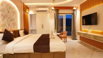 Habitación de hotel con cama, televisión, balcón y vista al exterior.