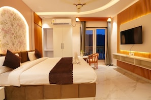 A hotel room with a bed, a TV, a balcony, and a view of the outdoors.