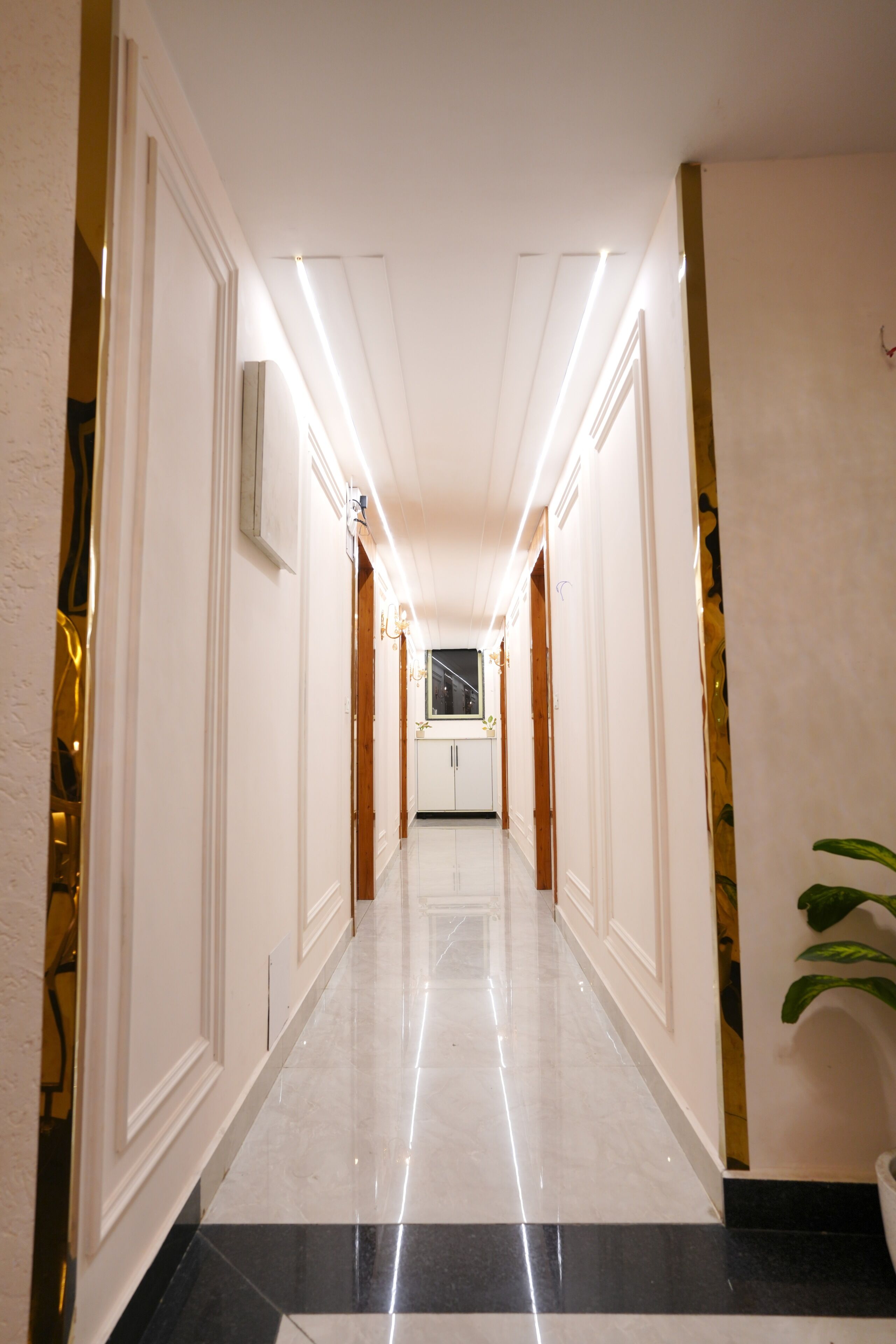 A hallway with a marble floor, white walls, and wooden doors.