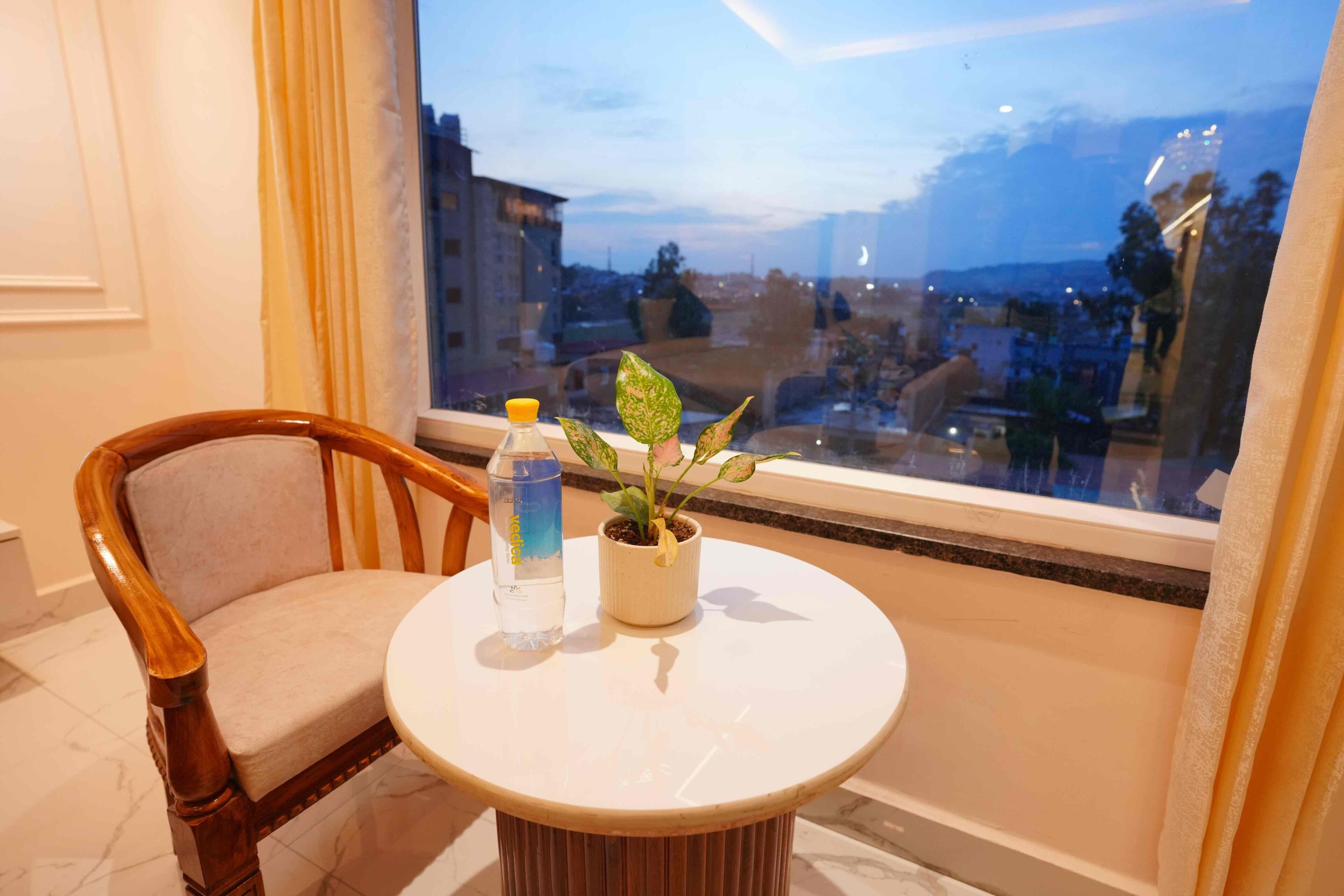 Una habitación con una mesa redonda, una silla, una botella de agua y una planta en maceta.