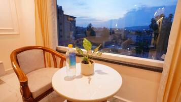 Una habitación con una mesa redonda, una silla, una botella de agua y una planta en maceta.