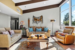 A modern living room with a sofa, coffee table, and a decorative wall piece. - Hot Tub + Covered Dining + Grill | Red Rock Views | Sage & Sandstone (Sedona)