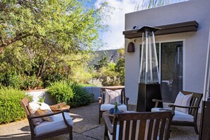 An outdoor seating area with two wooden chairs and a table, a small heater, and a view of a mountainous landscape. - Hot Tub + Covered Dining + Grill | Red Rock Views | Sage & Sandstone (Sedona)