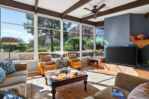 A spacious living room with a large TV, comfortable seating, and a view of a mountainous landscape. - Hot Tub + Covered Dining + Grill | Red Rock Views | Sage & Sandstone (Sedona)