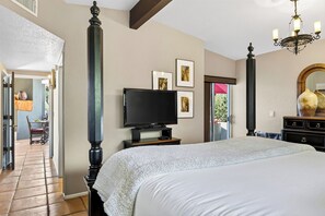 A bedroom with a large bed, a television, a mirror, and a door leading to a balcony. - Hot Tub + Covered Dining + Grill | Red Rock Views | Sage & Sandstone (Sedona)
