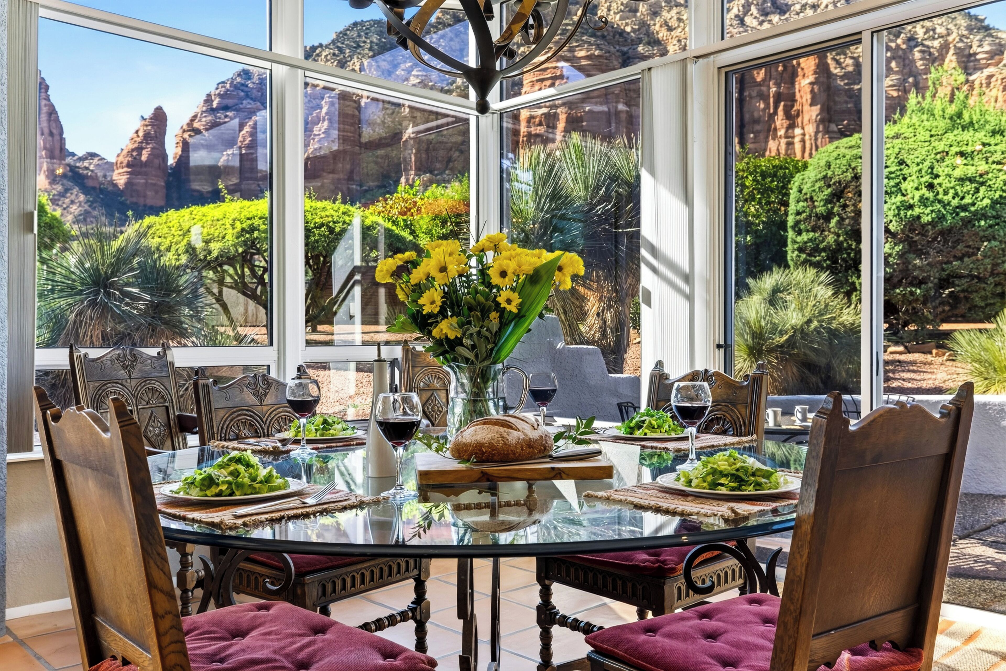 A dining area with a glass table and chairs, surrounded by a scenic mountain view.