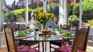 Zona pranzo con tavolo e sedie in vetro, con vista sulle montagne.