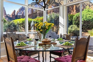 A dining area with a glass table and chairs, surrounded by a scenic mountain view. - Hot Tub + Covered Dining + Grill | Red Rock Views | Sage & Sandstone (Sedona)