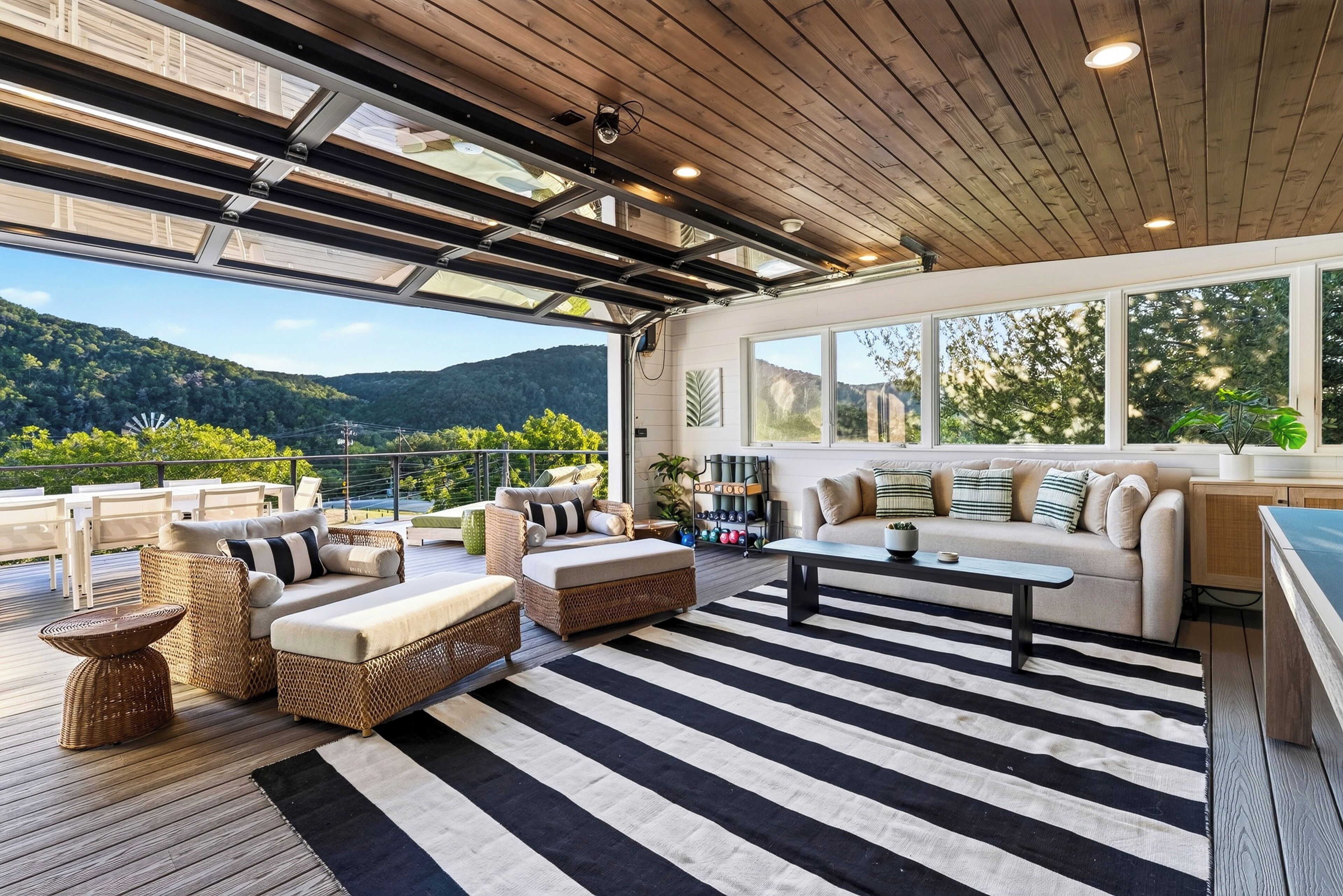 A spacious outdoor living area with a wooden deck, outdoor furniture, and a view of the mountains.