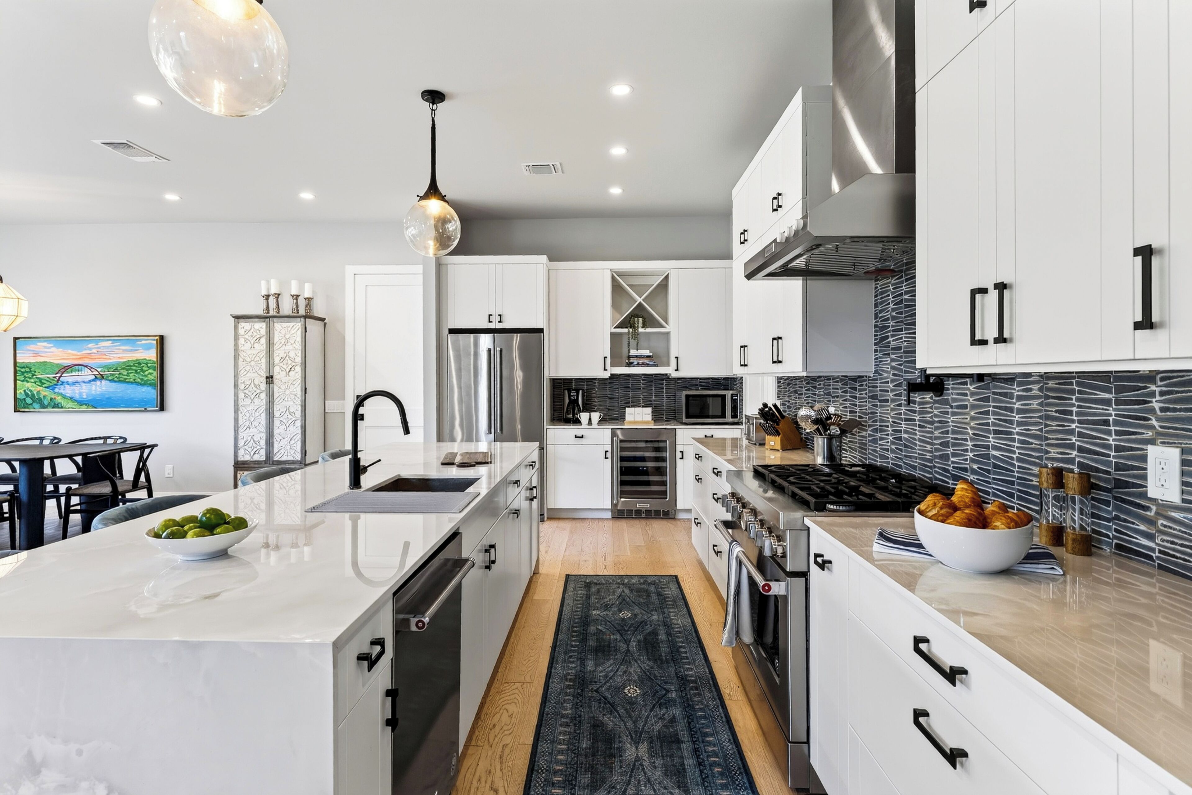 A modern kitchen with white cabinetry, stainless steel appliances, and a central island.