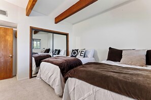Ein Schlafzimmer mit zwei Betten, einem großen Spiegel und einem Holzbalken an der Decke.