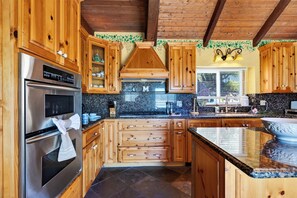 Eine Küche mit Holzausstattung, Edelstahlgeräten und einer Arbeitsplatte aus Granit.