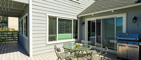 A deck with a glass-top table and chairs, a grill, and a screened patio area.