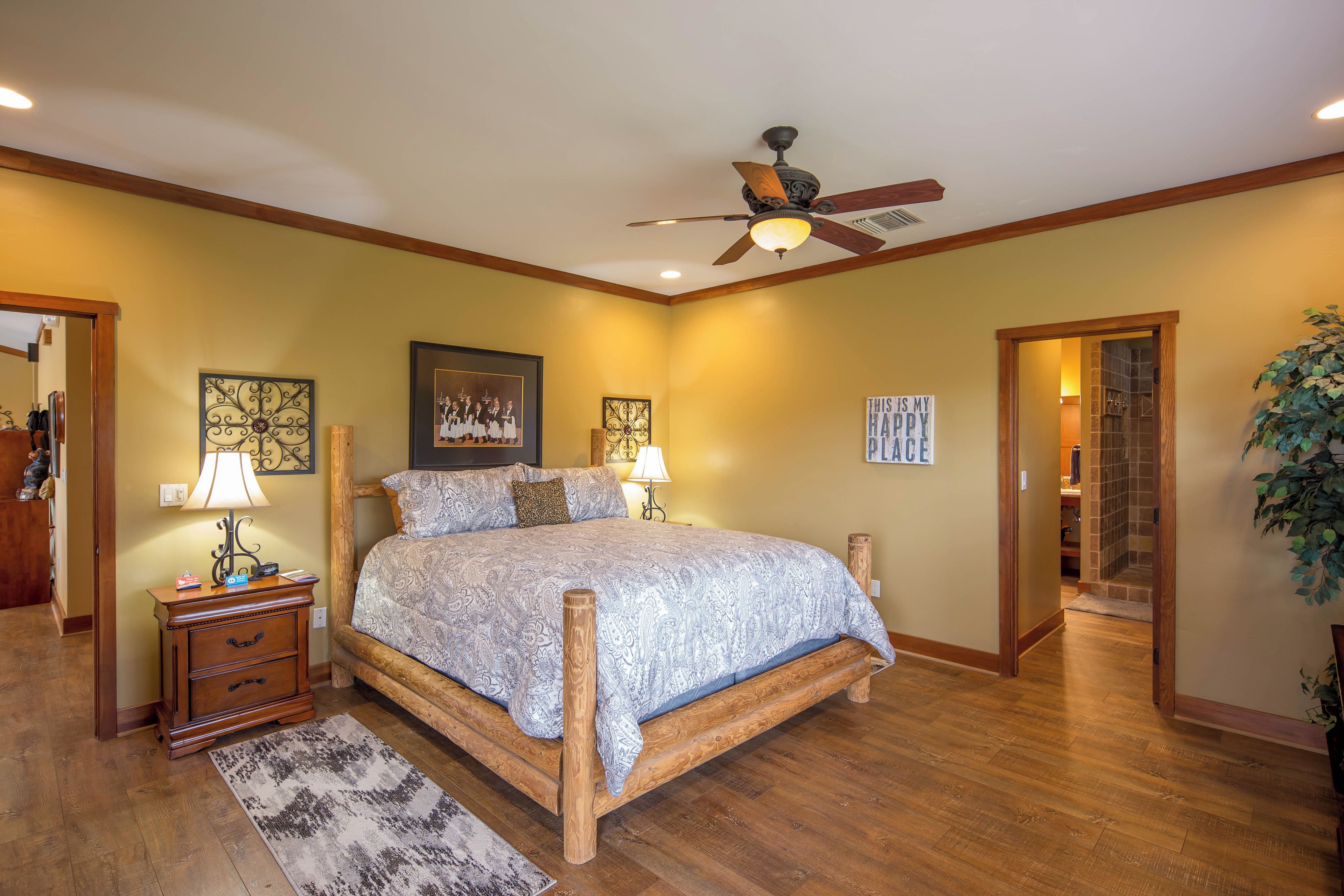 A bedroom with a wooden bed, a ceiling fan, and a nightstand with a lamp.
