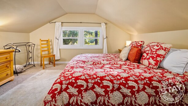 Ein Schlafzimmer mit Bett, Stuhl, Schreibtisch und Fenster.
