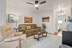 A living room with a sofa, armchair, coffee table, and a ceiling fan. There are framed pictures on the wall and a potted plant. - 3 BRs + Firepit + BBQ + Cornhole | Two Decks | Paso + Hideaway on Oak (Paso Robles)