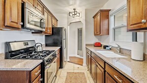 A compact kitchen with wooden cabinets, a stainless steel refrigerator, a gas stove, and a built-in oven. - 3 BRs + Firepit + BBQ + Cornhole | Two Decks | Paso + Hideaway on Oak (Paso Robles)