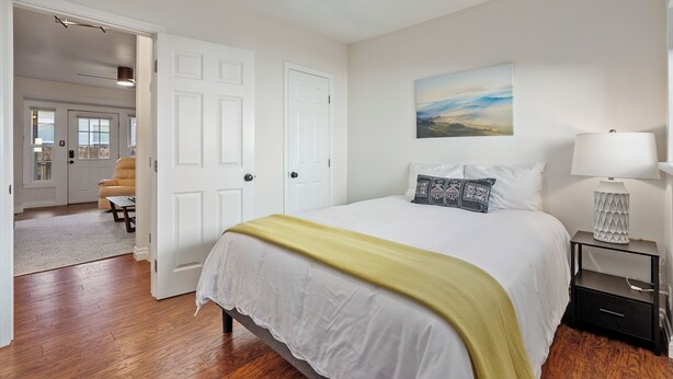 A bedroom with a bed, bedside table, lamp, and a painting on the wall. - 3 BRs + Firepit + BBQ + Cornhole | Two Decks | Paso + Hideaway on Oak (Paso Robles)