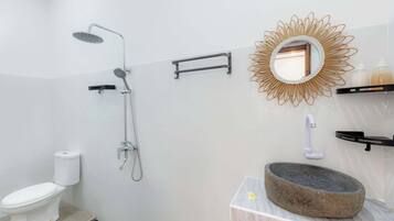 A bathroom with a shower, toilet, and a sink with a stone basin.