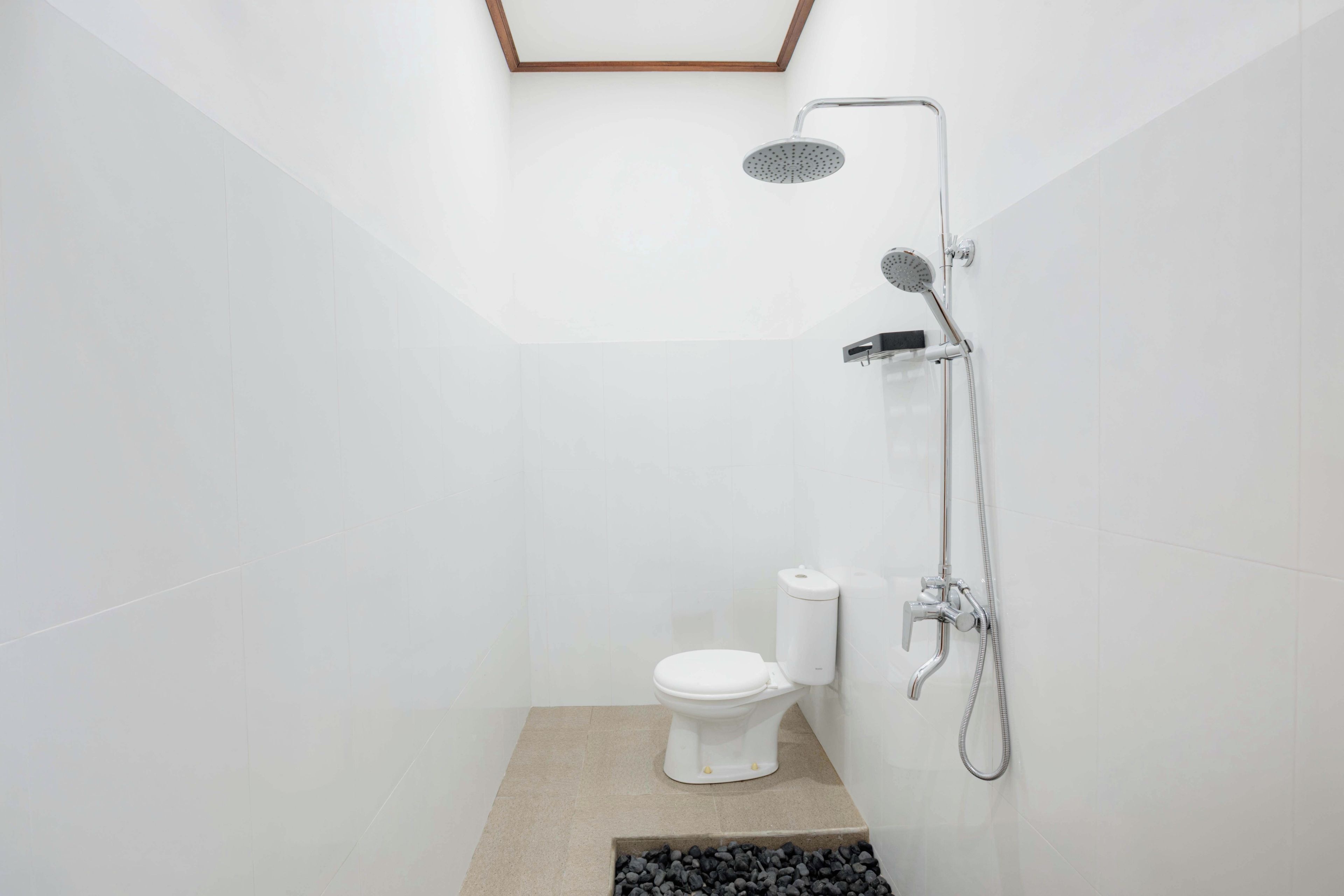 Une salle de bain moderne équipée d’une douche, de toilettes et d’un petit marchepied menant à un sol de couleur sombre.