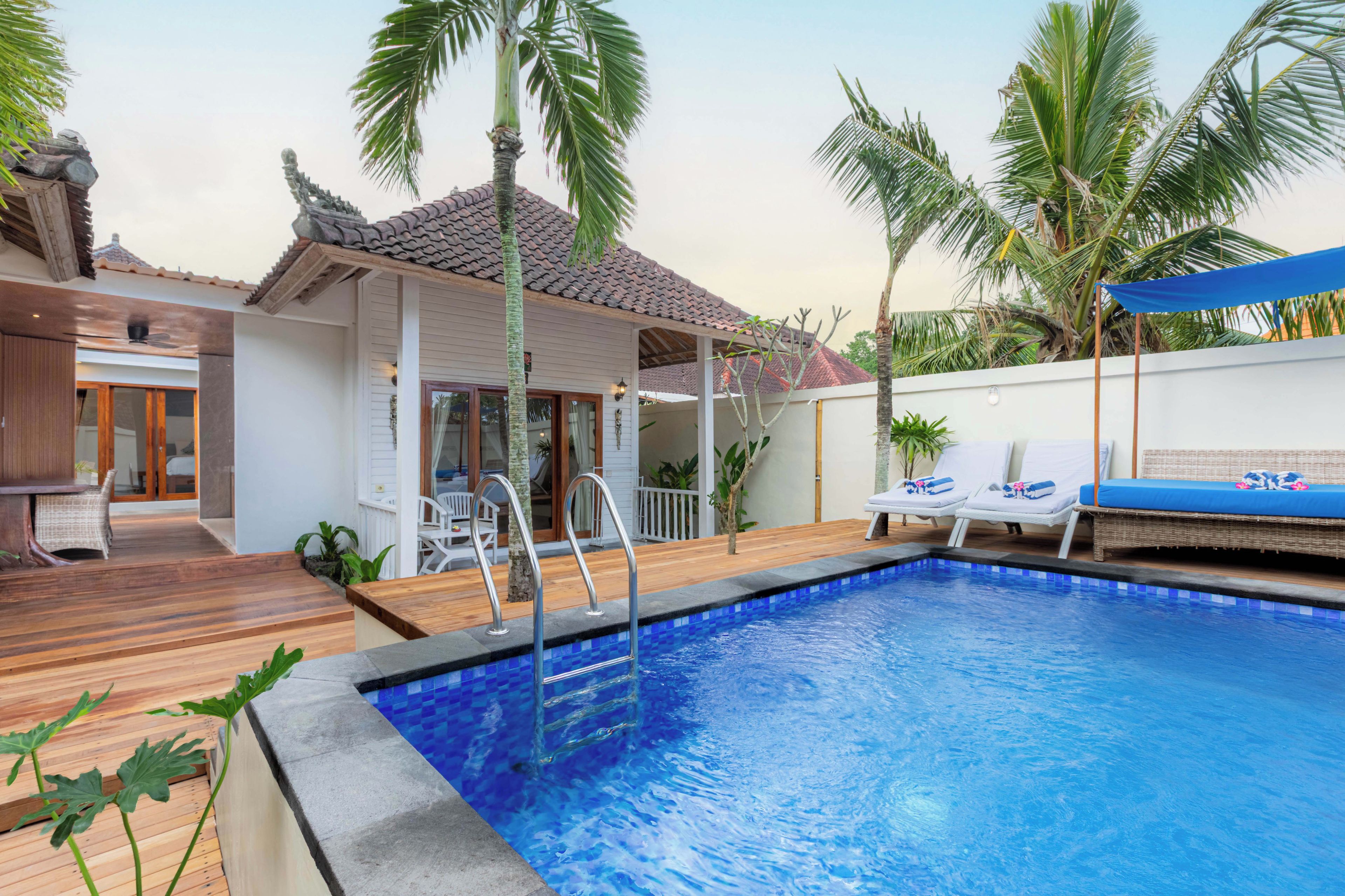 A swimming pool with a tiled edge, lounge chairs, and a covered seating area.