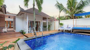 A swimming pool with a tiled edge, lounge chairs, and a covered seating area.