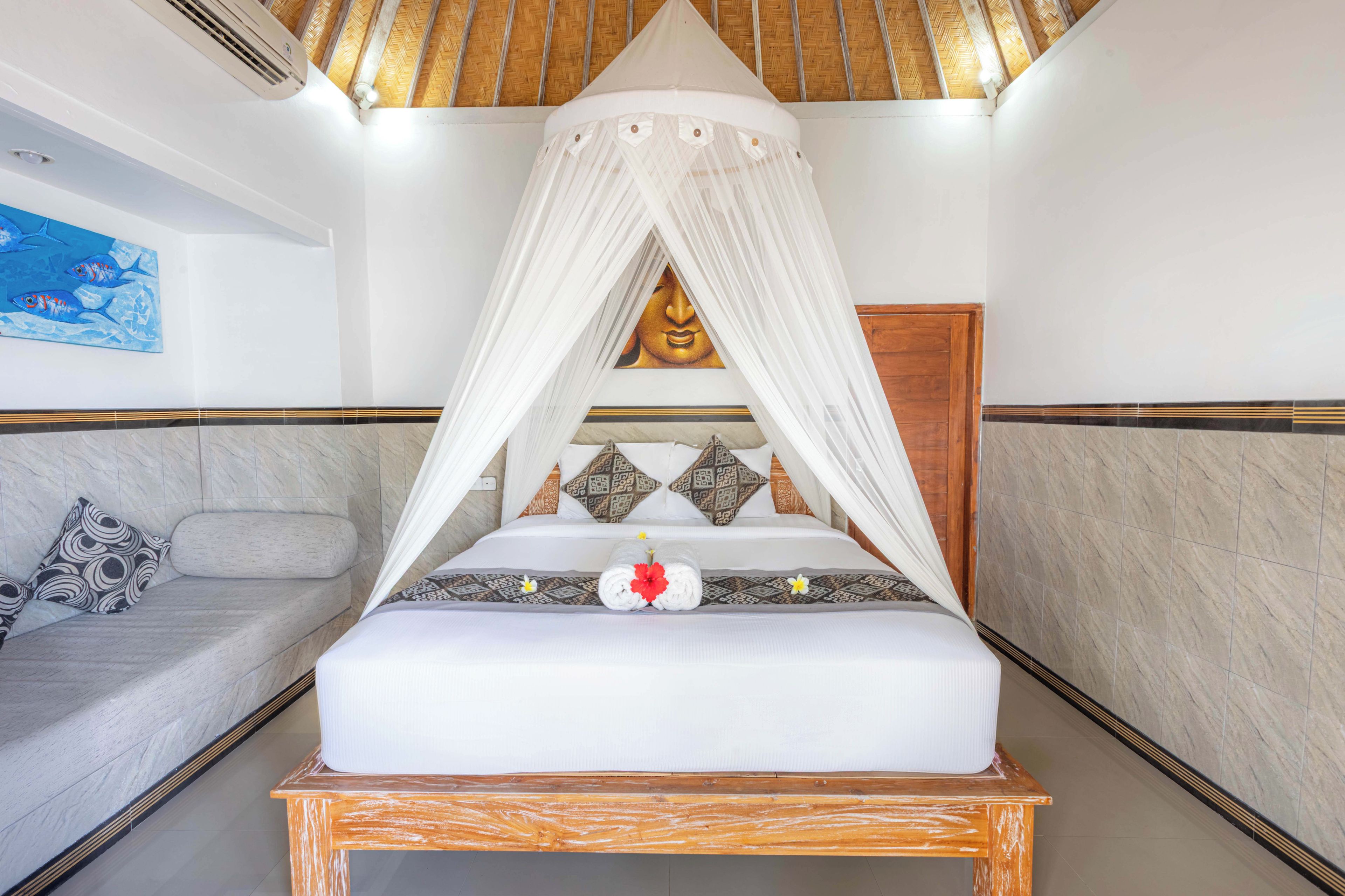 A bed with a canopy, a wall with a Buddha painting, and a blue artwork on the wall.
