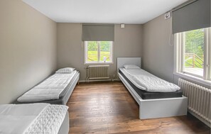 A room with two single beds, a radiator, a window with a view of greenery, and a ceiling fan. - 4 bedroom pet friendly home in Lilla Forsa (Lilla Forsa)