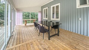 A covered outdoor dining area with a wooden deck, a table with chairs, and large windows. - 4 bedroom pet friendly home in Lilla Forsa (Lilla Forsa)