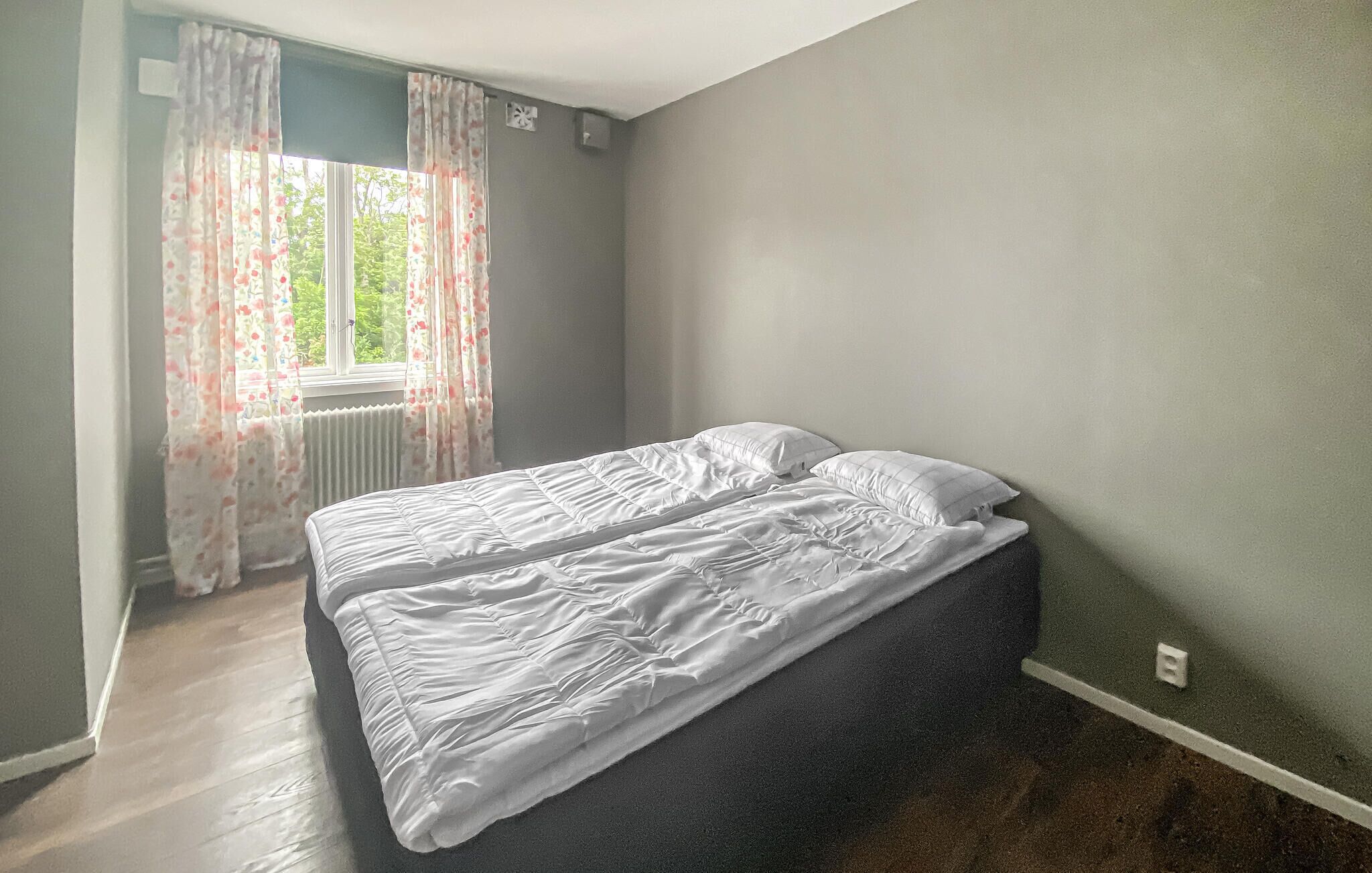 A bedroom with a bed, a window with curtains, and a radiator.