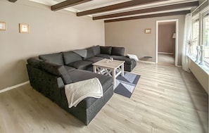 A living room with a dark-colored sectional sofa, a small white table, and a patterned rug. - 3 bedroom cozy home in Mönsterås (Mönsterås)