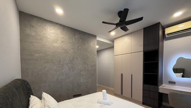 Una habitación de hotel moderna con cama, escritorio, armario y ventilador de techo.