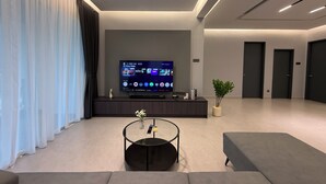 Una sala de estar moderna con un televisor de pantalla plana, una mesa de centro redonda y un sofá gris.