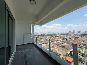 A balcony with a city view, a metal railing, and a tiled floor.