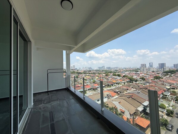 A balcony with a city view, a metal railing, and a tiled floor.