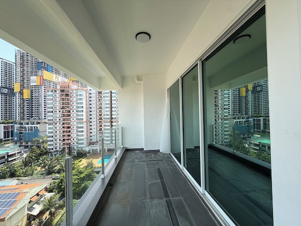 A balcony with a view of high-rise buildings and a swimming pool.