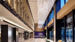 A spacious lobby with a high ceiling, a seating area with chairs and a table, and a reception desk. - Hampton by Hilton Beijing Dahongmen (Beijing)