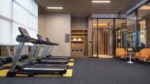 A gym with treadmills, a reception desk, and a seating area with chairs. - Hampton by Hilton Beijing Dahongmen (Beijing)